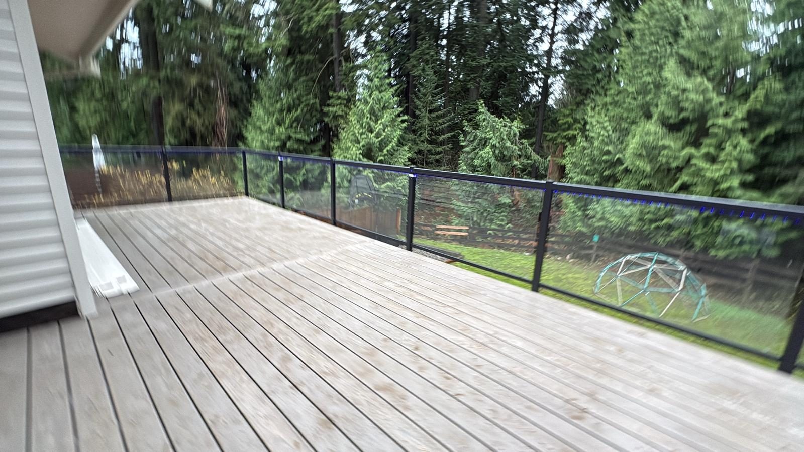 Glass railing on a wood deck facing the forest in Port Moody