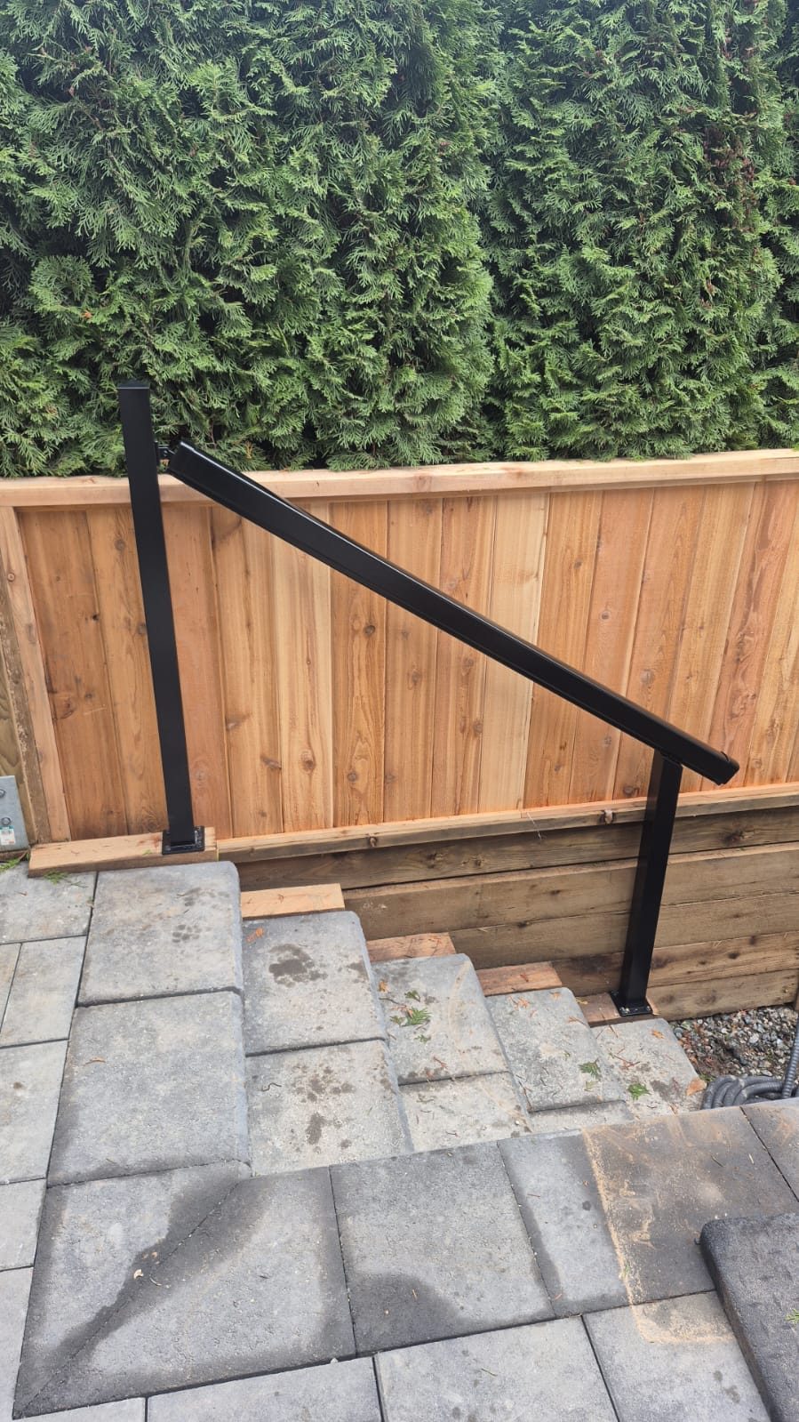 Black aluminum handrail on stone steps in Delta