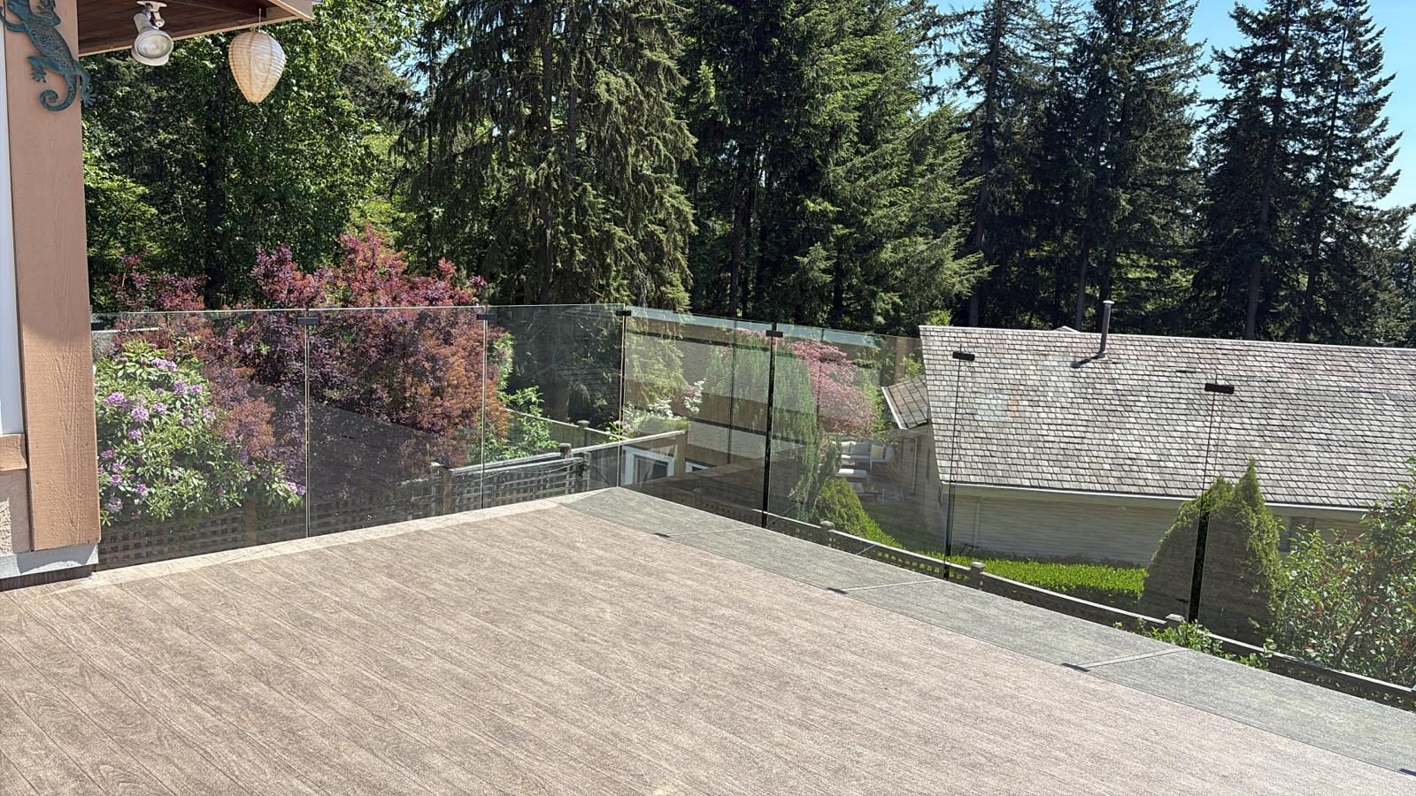 Glass railing around a stone patio overlooking the trees on a North Vancouver hillside