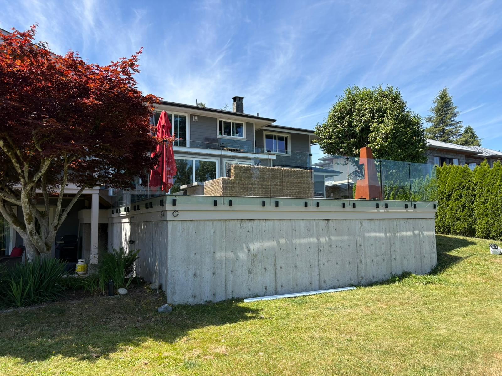 Glass railing on top of a concrete retaining wall in North Vancouver
